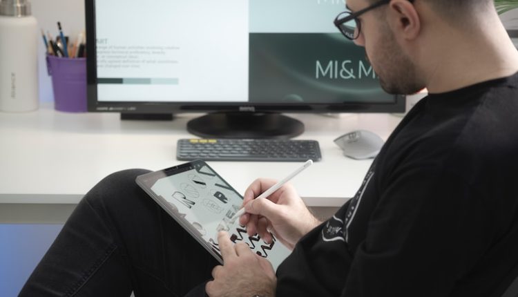 man in black long sleeve shirt sitting beside black flat screen computer monitor